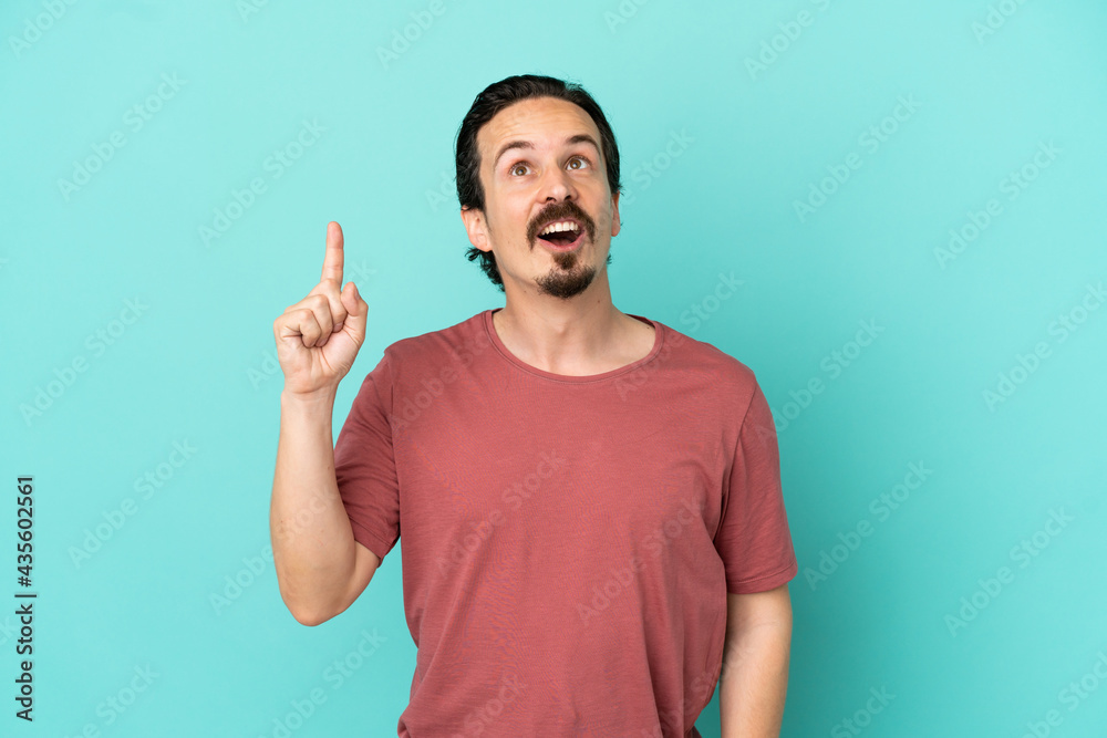 Young caucasian man isolated on blue background pointing up and surprised Young caucasian man isolated on blue background pointing up and surprised