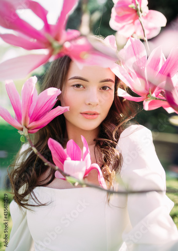 Portrait of woman in garden among blooming magnolia.