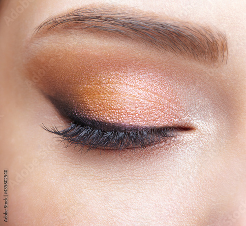 Closeup macro shot of closed human female eye. Girl with perfect skin and  pink eyes shadows
