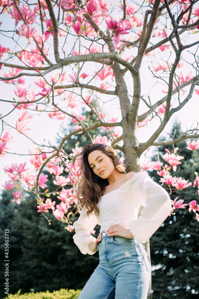 Woman stands in garden under the blooming magnolia tree. Woman stands in garden under the blooming magnolia tree.