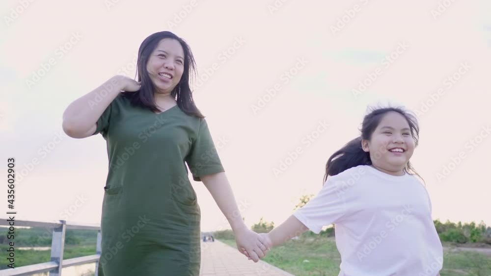 Front view of Asian mom and kid holding hand and running outdoor on track in the evening, spending time together and having fun, Mom and daughter concept, lovely family Front view of Asian mom and kid holding hand and running outdoor on track in the evening, spending time together and having fun, Mom and daughter concept, lovely family