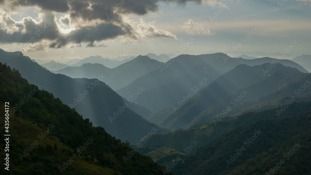 Beautiful landscape with layers of mountains and rays of light coming through the clouds, near Khaling village, Trashigang, Bhutan