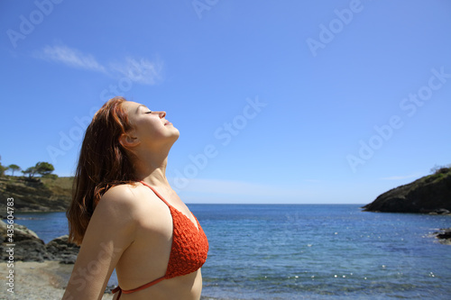 Fototapeta Naklejka Na Ścianę i Meble -  Woman in bikini breathing fresh air on the beach