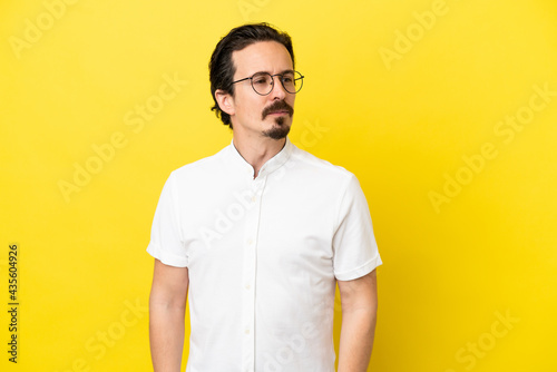 Young caucasian man isolated on yellow background looking to the side © luismolinero