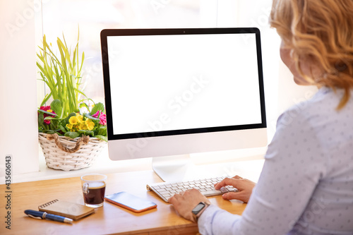 Woman working on desktop computer with empty white screen