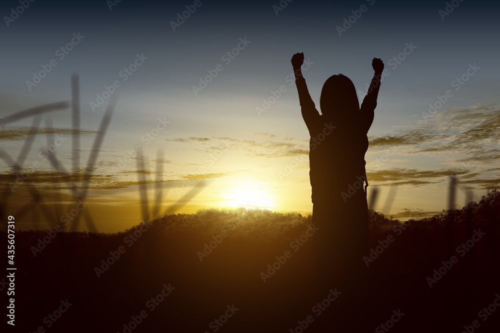 Silhouette of a little girl with a backpack with happy expression with sunset background