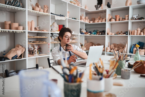 Serious pot maker clicking on computer while drinking tea