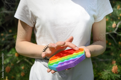 Teenage Girl play in sensory anti stress Pop It in hexagon shape toy in park. Close up. Outdoors.