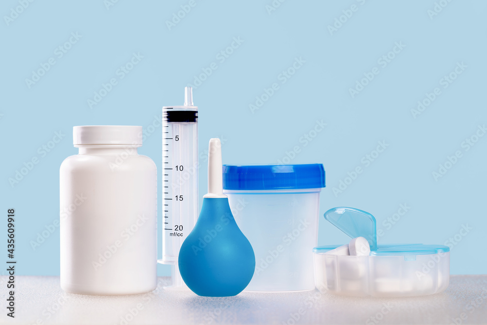 Medical mockup plastic jars and syringe on blue with plaster roll. Copy space. Lab or sample tests concept. Daily pills container