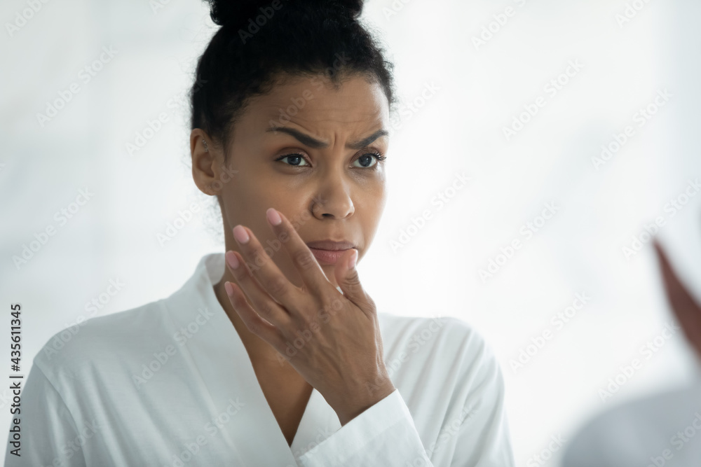 Annoyed frustrated young Afro American woman feeling dryness, after morning  shower, looking in mirror, scanning facial skin with frowning face.  Skincare problems, dry skin concept Stock Photo | Adobe Stock