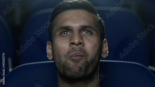 Closeup of a young man in a movie theatre enjoying the film and eating popcorn