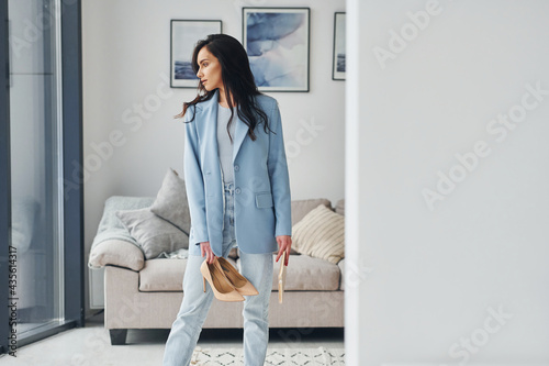 Domestic room. European woman in fashionable stylish clothes is posing indoors