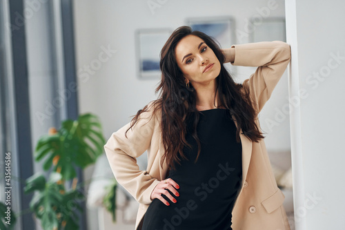In black dress and jacket. European woman in fashionable stylish clothes is posing indoors Free Download In black dress and jacket. European woman in fashionable stylish clothes is posing indoors - GFXLoad