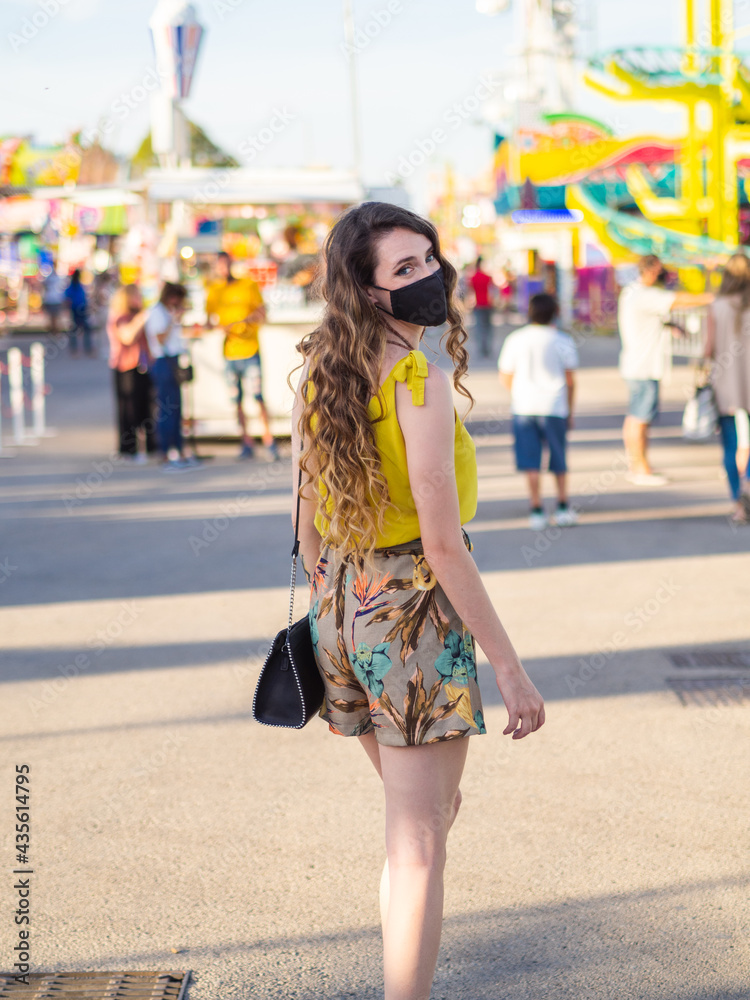 Mujer joven con mascarilla disfrutando de las vacaciones de verano en un parque de atracciones