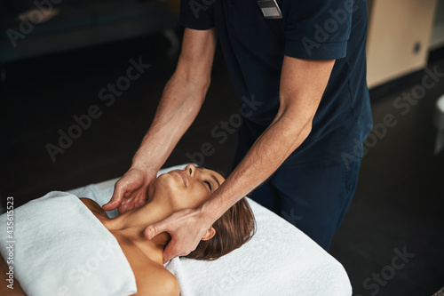 Professional experienced male therapist in blue uniform healing body treatment in health clinic