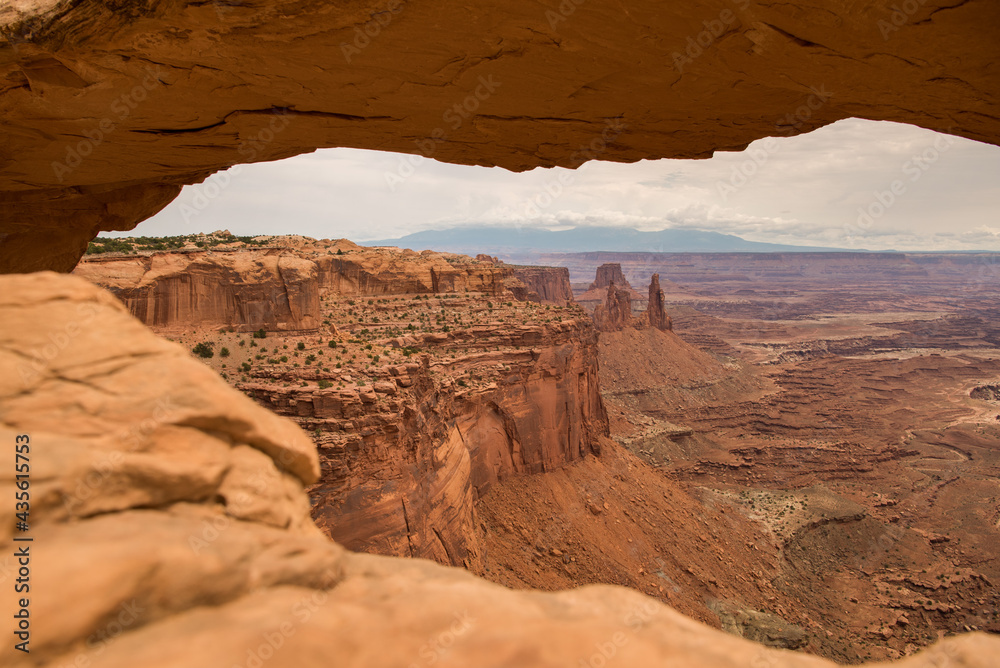 Looking through the window that is Mesa Arch at Canyonlands National Park Utah out into the vast red rock canyon layers.