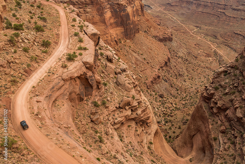 Aerial view of off road vehicle on dirt road winding through Canyonland Nationals Park in Utah.