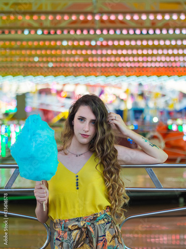 Mujer joven disfrutando de un algod  n de az  car en la feria o parque de atracciones