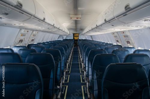 Rows of black leather seats and porthole windows in commercial aircraft cabin. Economy class chairs of airplane. Background, copy space, close up.
