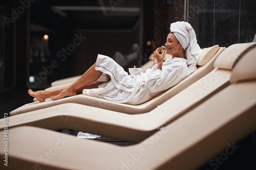 Beautiful charming Caucasian woman with towel on head sitting on deck chair in spa resort hotel