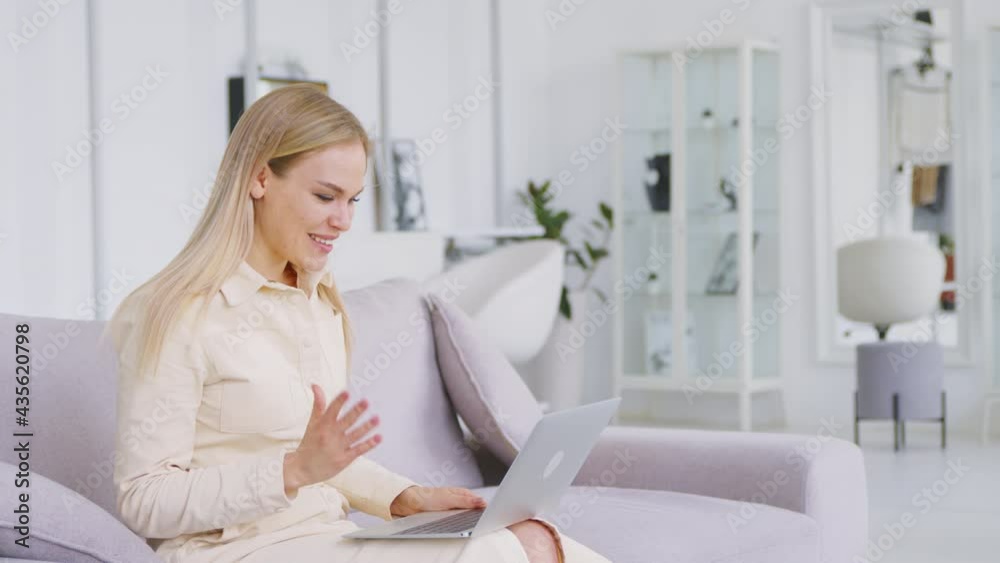 Young attractive woman holding video conference remotely from white room at home. Smiling woman communicating by video live Young attractive woman holding video conference remotely from white room at home. Smiling woman communicating by video live