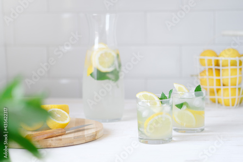Fresh lemon lemonade with mint in bottle on kitchen table with ingredients. healthy nutrition diet concept. White background.