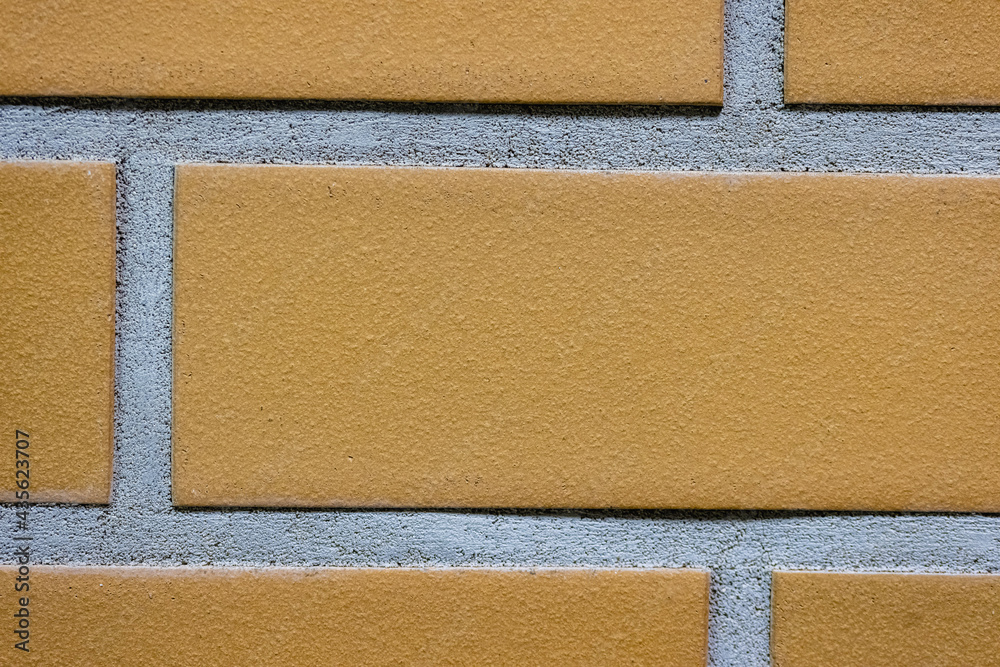 Fototapeta premium Close-up texture of a yellow brick wall with a gray seam