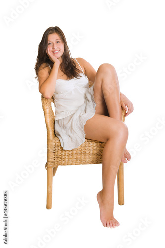 Happy young woman sitting on a wicker chair, isolated on white background