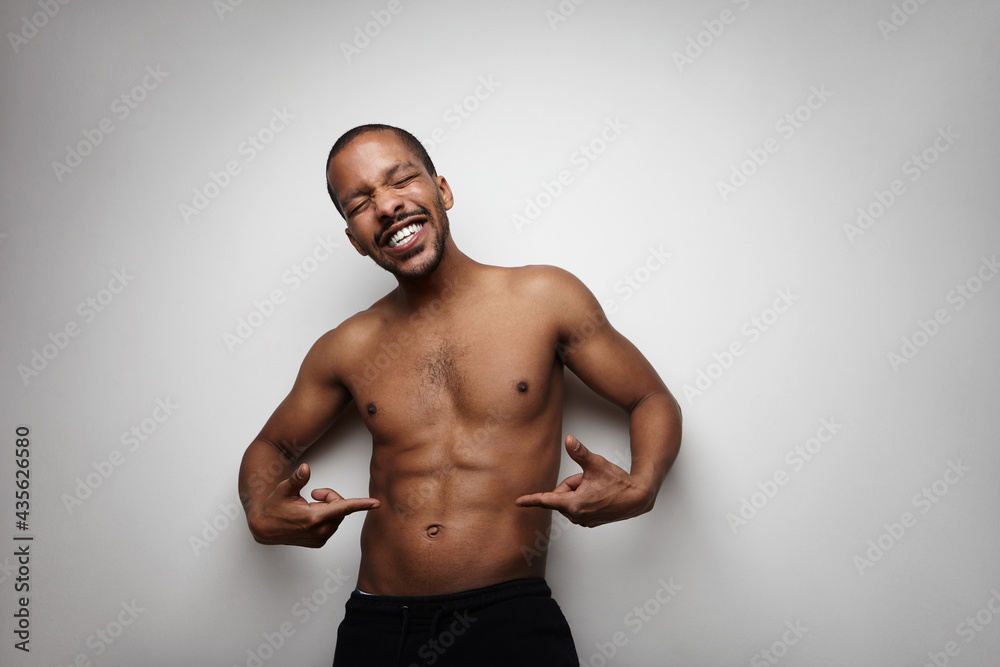 Portrait of bald black man, showing his perfect body, posing over white wall. Portrait of bald black man, showing his perfect body, posing over white wall.