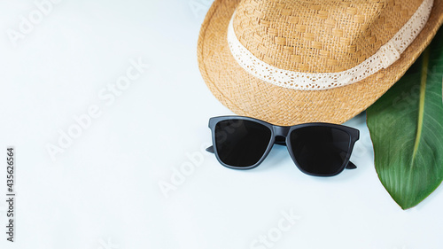 Front view of straw hat and sun glasses on light blue background. Image with copy space. Vacation concept