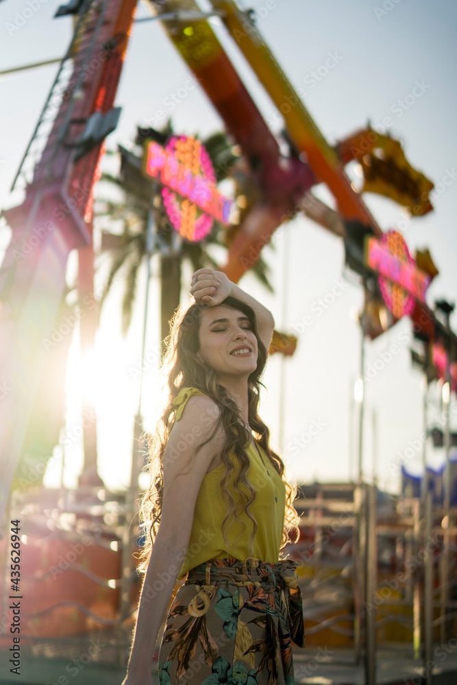 Mujer joven en vestido de verano divirtiéndose en el parque de atracciones