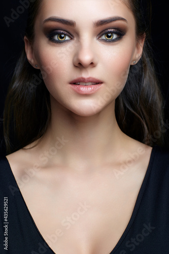 Beauty portrait of young  woman. Brunette girl with evening female makeup and black dress