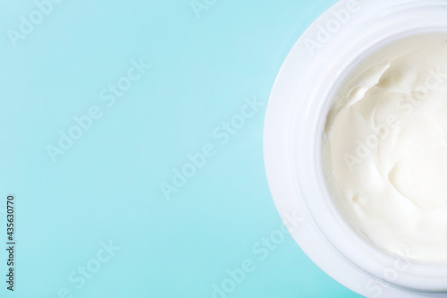jar of white cream on blue background with copy space. concept of cosmetics, skin care.