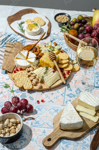 Cheese plate with variety of appetizers on table. Fresh brie cheese and camembert cheese whith crackers, pears, grapes, olives, rosemary, orange jam, orange jam, nuts, honeycomb and wine.