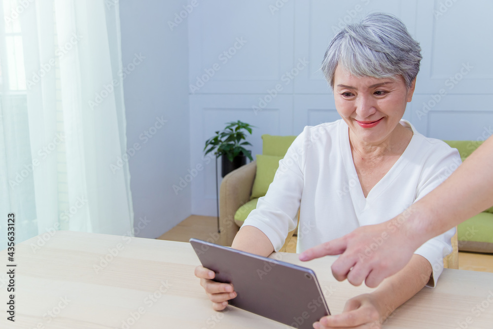 Young friend teaching older woman to use computer tablet , pointing at screen, elder woman asking questions about mobile device. Elderly and technology concept. Young friend teaching older woman to use computer tablet , pointing at screen, elder woman asking questions about mobile device. Elderly and technology concept.