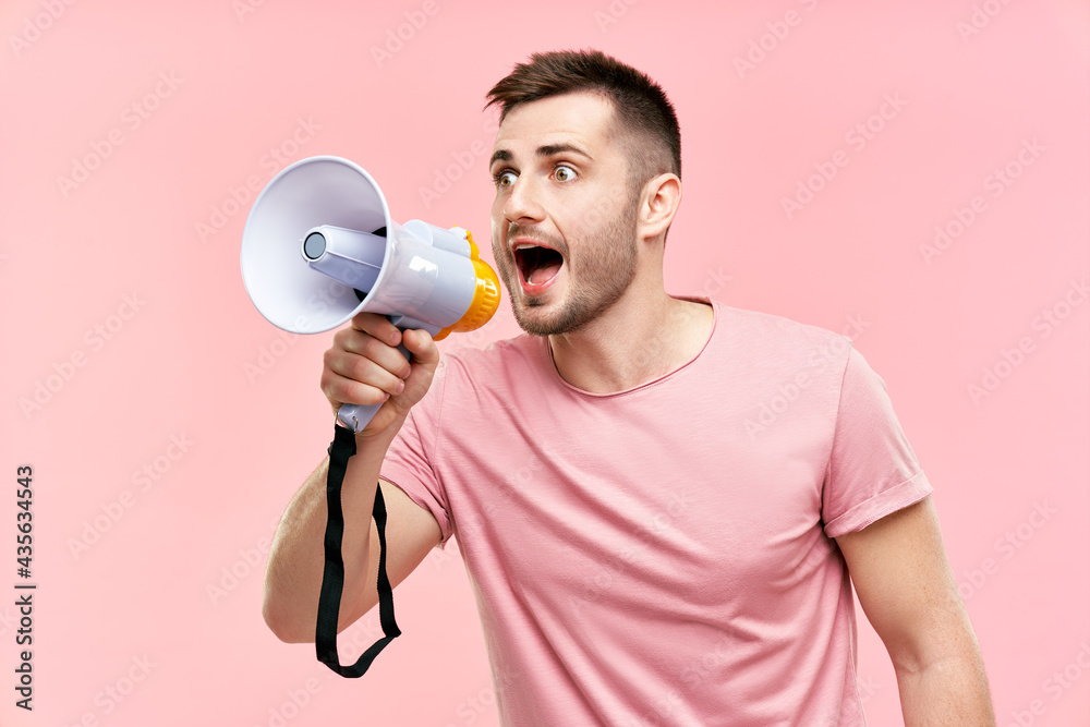 Funny young man shouting loud holding a megaphone over pink background  Stock Photo | Adobe Stock