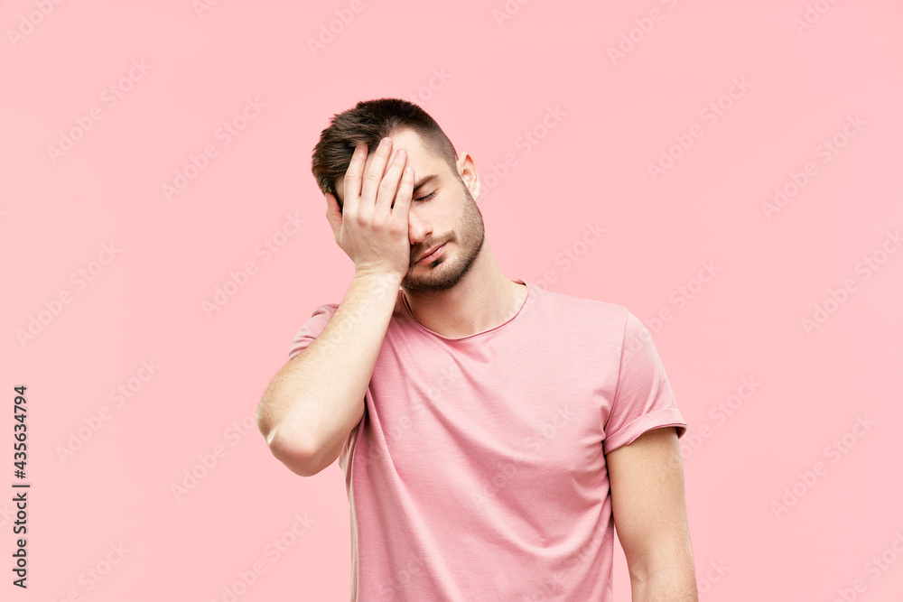 Tired disappointed young man with face palm gesture over pink background Tired disappointed young man with face palm gesture over pink background