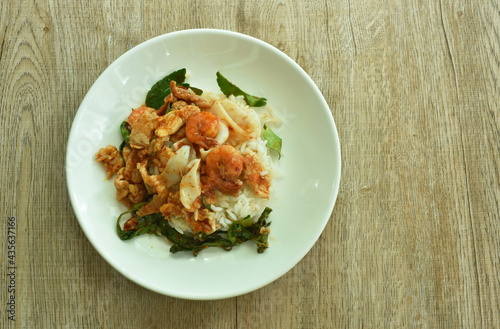 spicy stir fried shrimp and squid curry with meat topping rice on plate