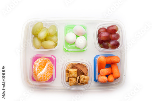 School lunch box snacks for kids over white background. Back to school. Healthy and fun snacks option for parents. Cute food art creative concepts. Bows with fruits and vegetables, top view.