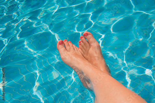 Woman feet at the swimming pool, turquoise blue water © Delphotostock