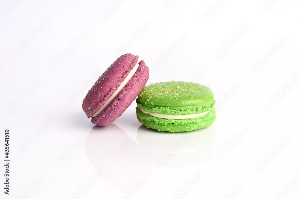 Two purple and green macarons cookies on a white background.. Two purple and green macarons cookies on a white background..