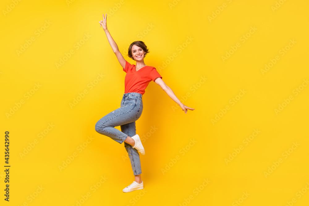 Full size profile photo of cool brunette optimistic lady dance wear red t-shirt jeans sneakers isolated on yellow color background