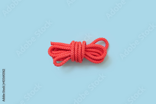 Pink gym and sport rope with a knot on blue background