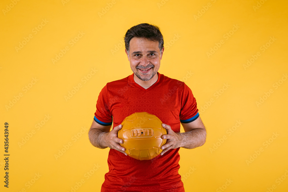 Soccer fan with red jersey and a retro ball in his hands