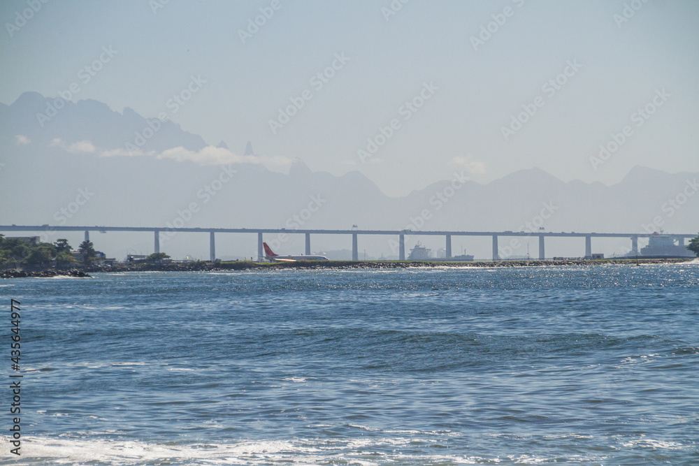Obraz premium Guanabara Bay, Santos Dumont Airport, Rio x Niteroi Bridge, and the Serra dos Orgaos in the background in Rio de Janeiro, Brazil.