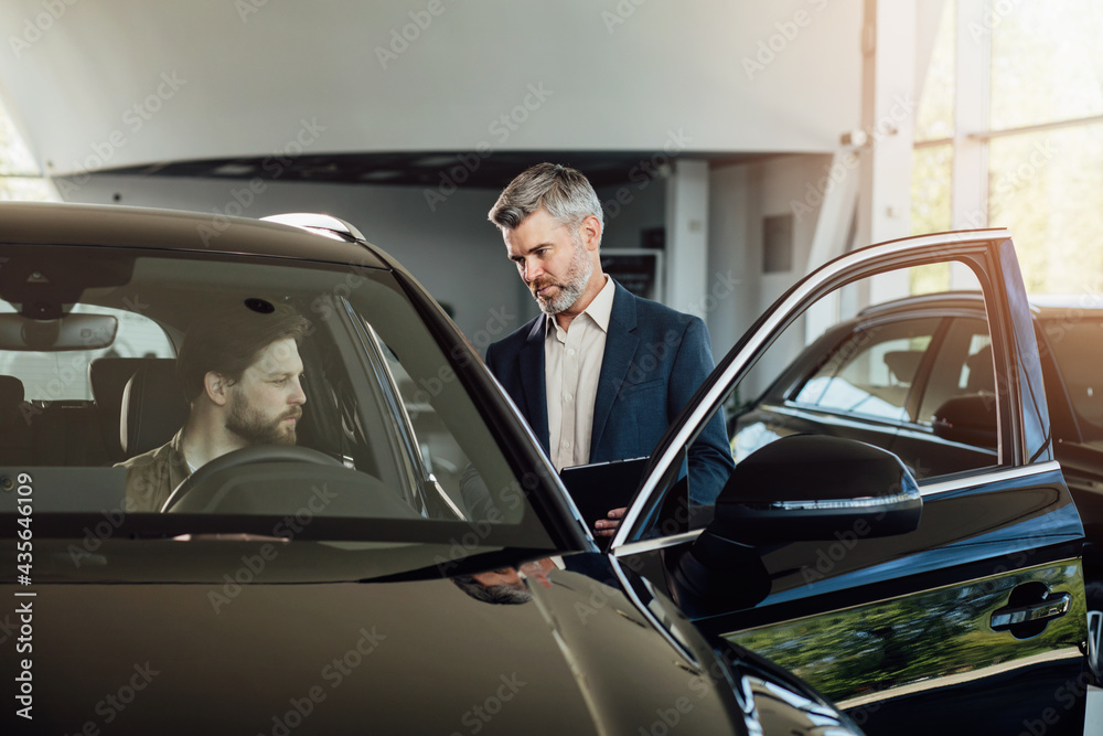 Buying a new car. Car dealer selling car using digital tablet. Buying a new car. Car dealer selling car using digital tablet.