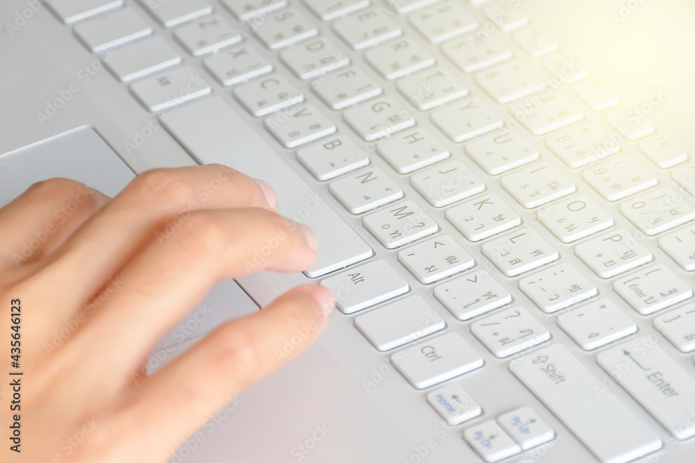 A woman's hand pressing a spacebar button on a white notebook A woman's hand pressing a spacebar button on a white notebook