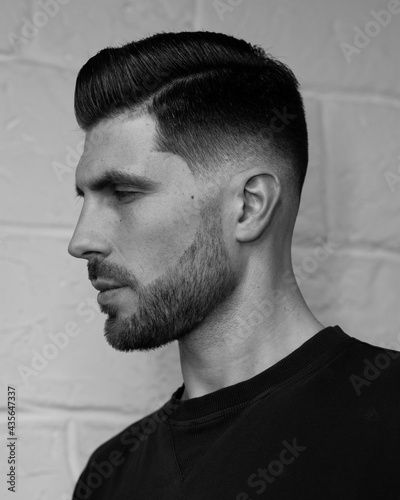 portrait of a man with stylish haircut on the white wall background