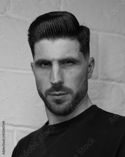 portrait of a man with stylish haircut on the white wall background