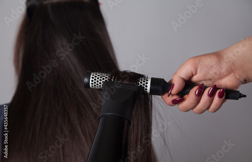Professional Hairdresser female drying caucasian woman's hair.